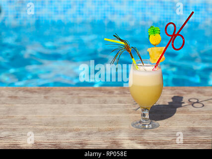 Bicchiere di cocktail pinacolada permanente sulla piscina listello in un resort tropicale Foto Stock