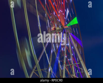 Carnival ride che mostra la filatura ruota panoramica Ferris in azione- lunga esposizione shot. Foto Stock