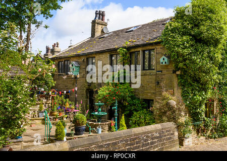 Attraente e caratteristico tradizionale cottage in pietra con funzioni ornamentali in giardino con patio (fontana & piantatrici) - Haworth, West Yorkshire, Inghilterra, Regno Unito Foto Stock