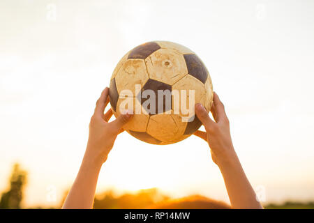 Sport outdoor foto di bambini di divertirsi giocando a calcio per esercitare sotto il crepuscolo Cielo di tramonto. Foto Stock