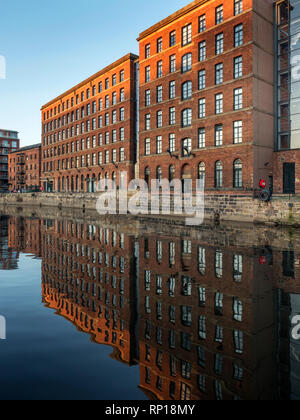 Convertite gli edifici adibiti a magazzino si riflette nel fiume Aire al tramonto Leeds West Yorkshire Inghilterra Foto Stock