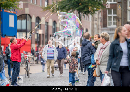 L'uomo gigante rendendo le bolle di sapone per il divertimento di persone al mercato e soprattutto cattura l'attenzione dei bambini a Groningen sabato mark Foto Stock