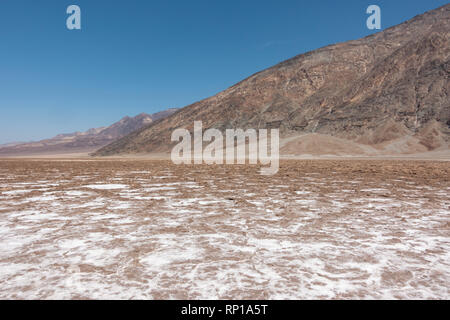 Guardando verso Badwater Road verso Mt Perry attraverso la crosta di sale, bacino Badwater, Parco Nazionale della Valle della Morte, California, Stati Uniti. Foto Stock