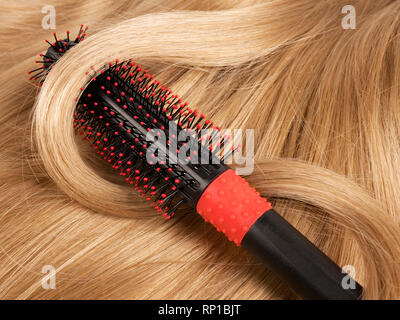 Bionda ondulata capelli umani lo sfondo con un pettine Foto Stock