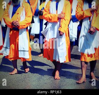 A piedi nudi di seguaci della religione Sikh durante una marcia su strada con vitnage effetto antico Foto Stock
