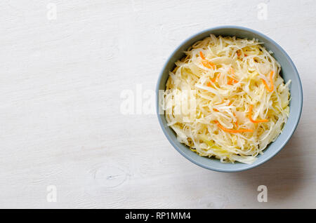 Vista superiore della ceramica grigia ciotola piena di materie cavolo tagliato e la carota bianca sul tavolo in legno di superficie con sfondo spazio copia Foto Stock