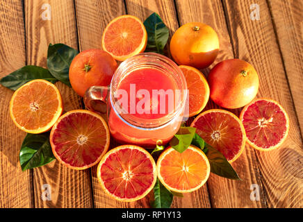 Il sangue di succo di arance con frutta fresca su sfondo di legno.colpo all'aperto sotto il sole Foto Stock