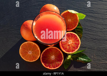 Sangue rosso succo di arance su una piastra di ardesia. Vista superiore Foto Stock