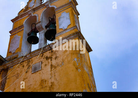 Vecchia chiesa gialla con massicce campane e cielo blu in background Foto Stock