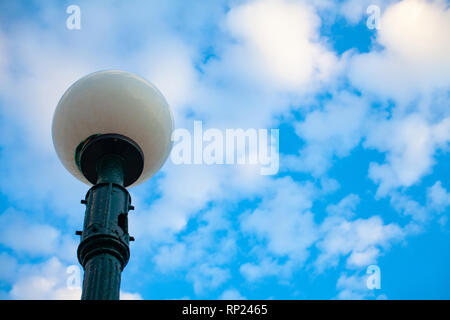 Bianco rotondo ball street lampadina con cielo nuvoloso dietro Foto Stock
