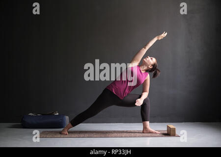 Donna facendo la Posizione laterale ad angolo di postura, Utthita Parsva Konasana. Foto Stock
