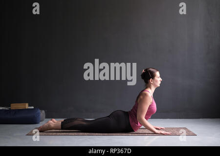 Bella sportiva montare yogini donna le pratiche yoga asana bhujangasana Foto Stock