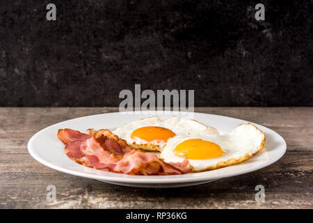 Uova fritte e pancetta per la colazione su un tavolo di legno. Close up Foto Stock
