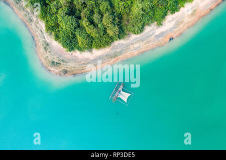 (Vista da sopra) stupefacente vista aerea di una costa verde di un'isola tropicale con una tradizionale barca da pesca in Nam Ngum serbatoio. Foto Stock