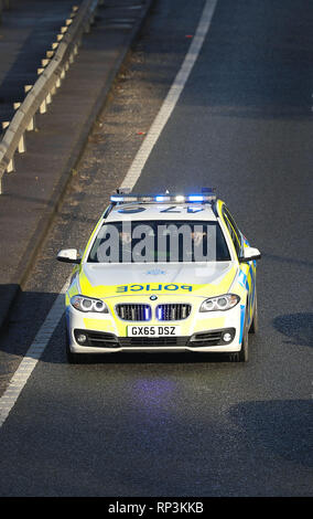 Gli automobilisti spostare in fuori il modo di una polizia del Sussex auto con le sue luci blu lampeggianti e la sirena suona come esso trascina verso il basso la A23 vicino a Brighton, East Sussex Foto Stock