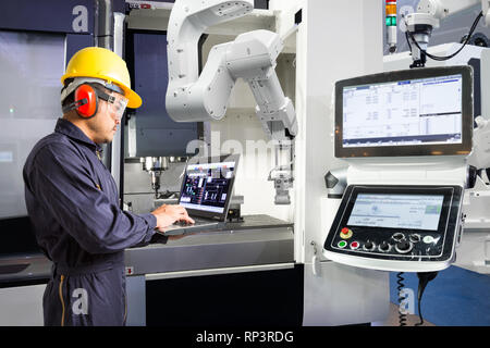 Tecnico di manutenzione utilizzando il computer portatile il controllo automatico di mano robotica con macchina CNC in smart factory, industria 4.0 concetto Foto Stock