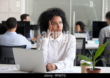 Nero di razza mista ufficio femmina lavoratore seduto alla scrivania in coworking space si sente male malsana soffre di mal di testa. La millenaria donna africana thinki Foto Stock