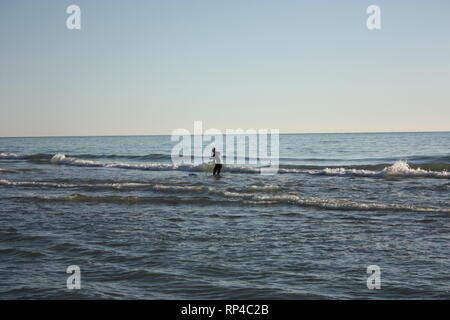 Uomo immerso nella pesca in mare e raccoglie tellines o vongole o altri frutti di mare su una giornata invernale Foto Stock