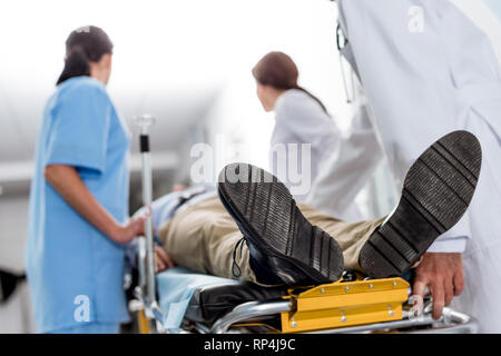 Medici e infermieri di trasportare inconscio paziente sulla barella Foto Stock