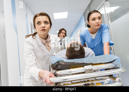 Medici e infermieri di trasportare inconscio paziente sulla barella Foto Stock