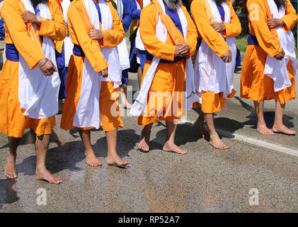 La religione sikh uomini con vestiti arancioni durante la cerimonia religiosa sulla strada Foto Stock