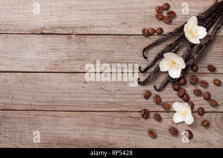 Bastoncini di vaniglia con chicchi di caffè avd fiore su un vecchio sfondo di legno con una copia dello spazio per il tuo testo. Vista dall'alto. Foto Stock