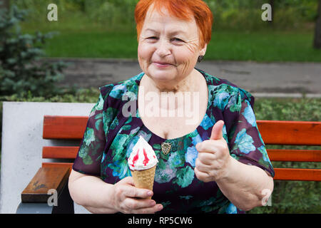 Donna anziana con gelato si trova in posizione di parcheggio sul banco in estate Foto Stock