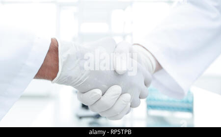 Stretta di mano con il bianco guanti medicali Foto Stock