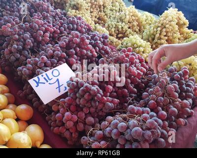 Organici di uve in vetrina al mercato del contadino. Acquirente femmina lato Foto Stock