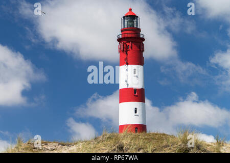 Faro sulla duna di sabbia contro il cielo blu con nuvole bianche sulla costa settentrionale in Germania Foto Stock