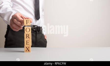 Consulente finanziario facendo una pila di blocchi di legno ortografia Forex con copia spazio per il lato destro dell'immagine. Foto Stock