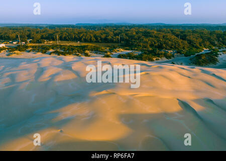 Le dune di sabbia e vegetazione dietro di loro al tramonto Foto Stock