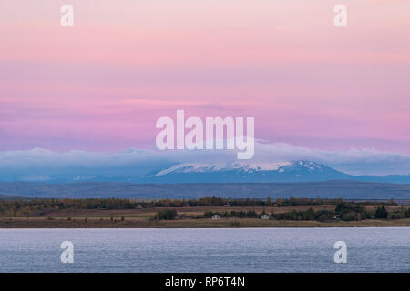 Antenna del paesaggio ad alto angolo di visione di Laugarvatn lago di acqua su un cerchio d'oro in Islanda con agriturismo in villaggio distante durante il tramonto rosa e blu Foto Stock