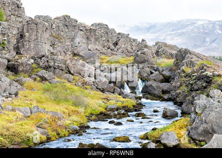 Thingvellir Parco Nazionale con fogliame di autunno in Islanda Golden Circle e una piccola cascata sul sentiero roccioso con acqua blu paesaggio Foto Stock
