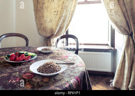 Rustico in legno vintage tavolo antico tovaglia e finestra in Ucraina o in Russia con piastre di verdure a fettine i cetrioli e pomodori cotti e cartine Foto Stock