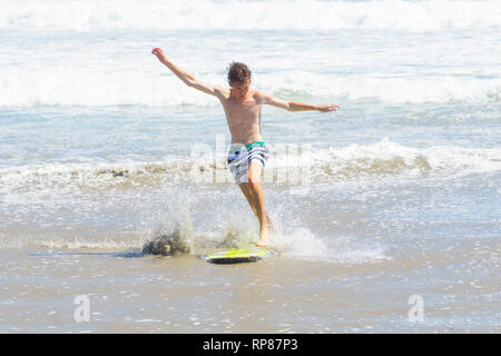 MOUNT MAUNGANUI NUOVA ZELANDA - 10 febbraio 2019: adolescente skim-imbarco in fondali bassi sulla spiaggia braccia allargate per equilibrio, Foto Stock