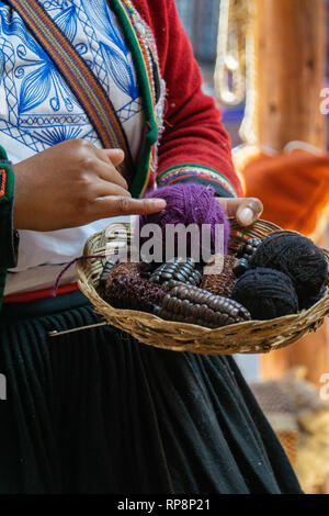 Donna in abito tradizionale prepara e coloranti filato di alpaca in Valle Sacra, regione di Cusco, Perù. Foto Stock