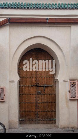 Stile tradizionale marocchino progettazione di un legno antico riad entrata porta. Nella vecchia Marrakech, Marocco. Tipico, vecchio, marrone intricate sculture, studded Foto Stock