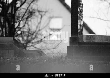 Il Menorah bokeh silhouette nella finestra di una casa vicino al soggetto ad atti vandalici tombe con simboli nazisti in blu spray-dipinte sulle tombe danneggiato - Cimitero Ebraico in Quatzenheim vicino a Strasburgo . Foto Stock