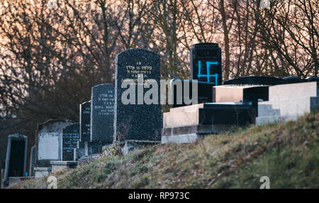 Basso angolo di visione del soggetto ad atti vandalici tombe con simboli nazisti in blu spray-dipinte sulle tombe danneggiato - vecchio cimitero ebraico in Quatzenheim vicino a Strasbourg Foto Stock