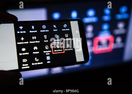 Los Angeles, California, Stati Uniti d'America - 21 febbraio 2019. Mani tenendo uno smartphone sullo sfondo dello schermo. MirrorShare è uno standard Huawei schermo Foto Stock
