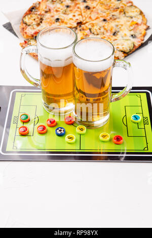 Immagine di due boccali di birra, calcio balilla, pizza Foto Stock