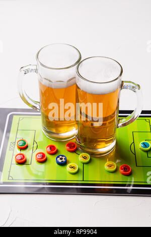 Immagine di due boccali di birra schiumosa, calcio balilla Foto Stock
