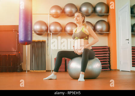 Yoga per donne in stato di gravidanza. Giovane bella ragazza incinta in sportswear fare yoga su fitball Foto Stock