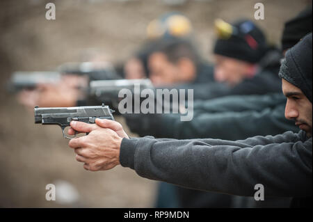 Gruppo di pratica civile pistola spara sul bersaglio all'aperto sul poligono di tiro. Team civili addestramento alle armi Foto Stock