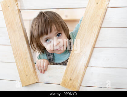 Carino bambino bambina guarda fuori dalla finestra del giocattolo di legno house Foto Stock