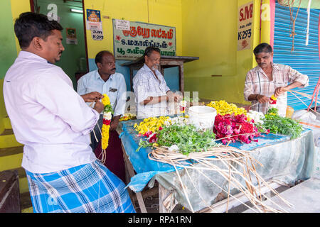 Amichevole titolari di stallo pongono per la fotocamera a Madurai flower market mentre fare ghirlande di fiori a vendere. Foto Stock