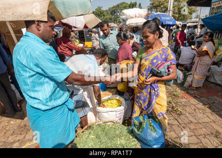 Un acquirente di fiori di consegnare il denaro al venditore per una transazione presso la trafficata movimentata di Madurai il mercato dei fiori. Foto Stock