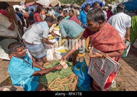 Un acquirente di fiori di consegnare il denaro al venditore per una transazione presso la trafficata movimentata di Madurai il mercato dei fiori. Foto Stock