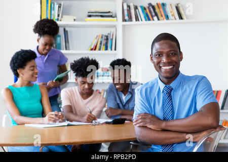 Bello africano insegnante maschio con la classe in aula della scuola Foto Stock